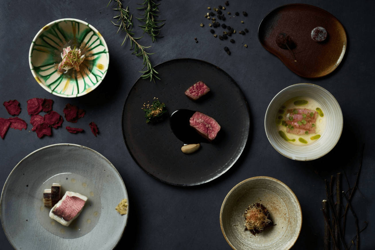 View from above of several round plates with small portions of food on them