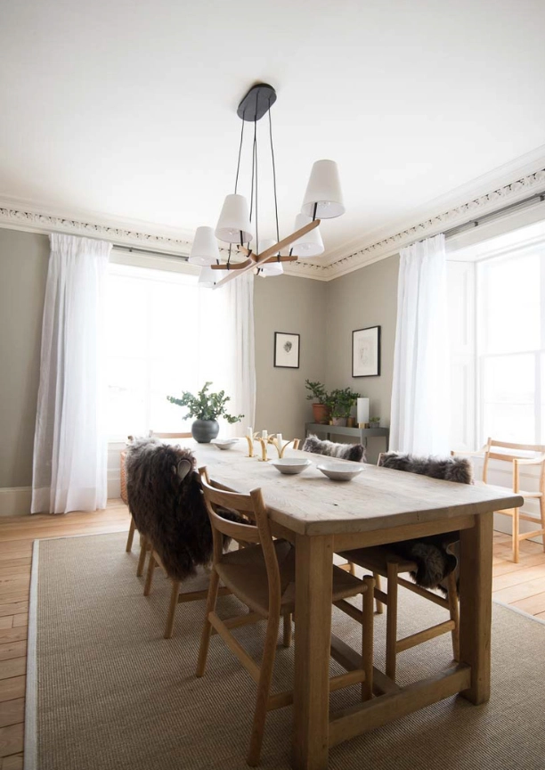 A bright dining area with a light wood table and chairs on a beige rug