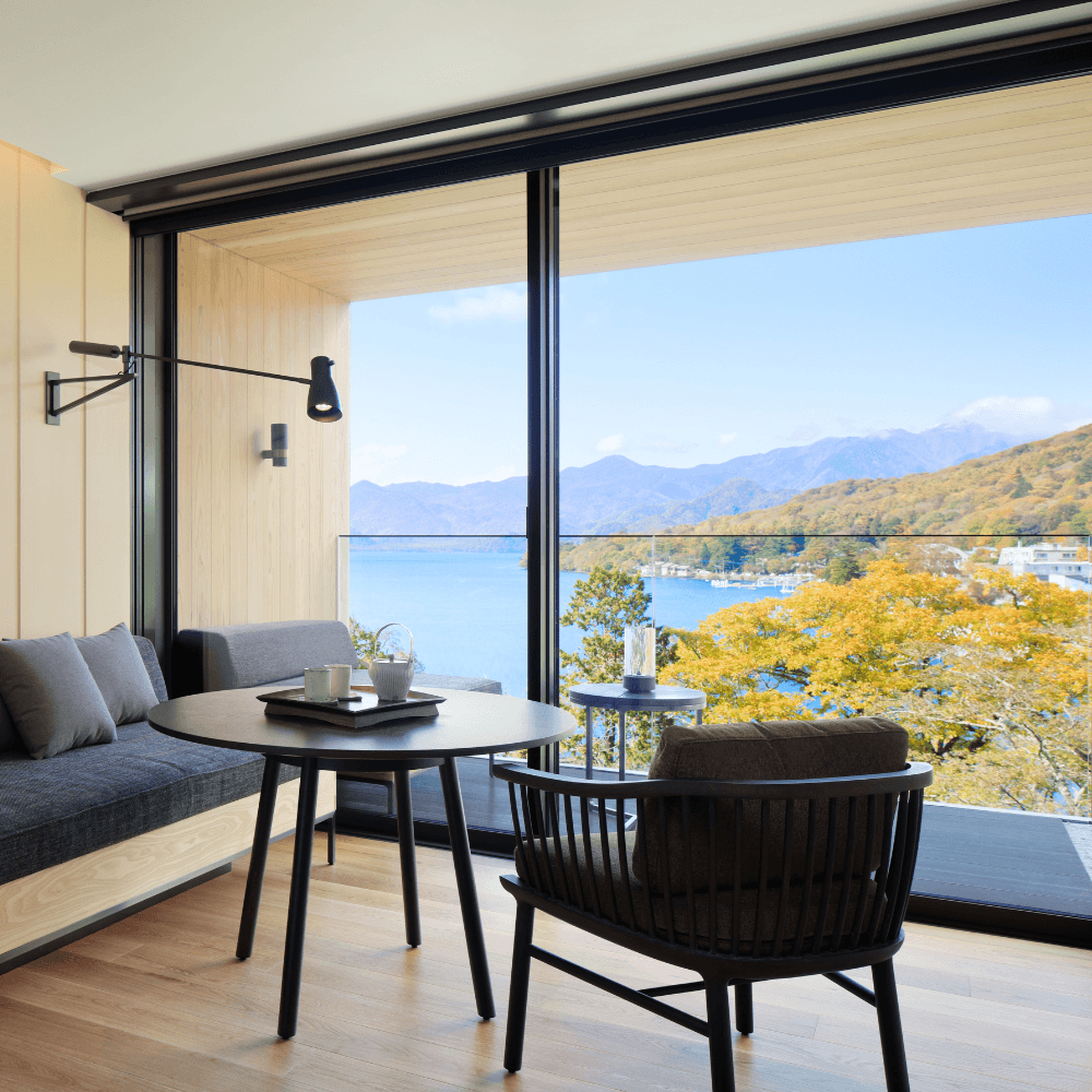 Modern hotel room with view of lake and yellow autumn leaves