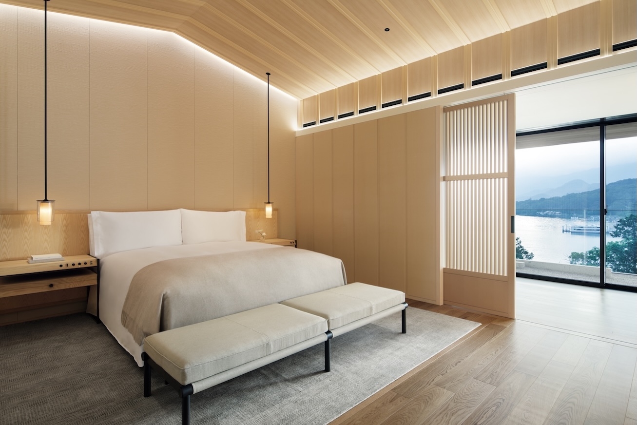 Modern hotel room with bed and lake view in the background