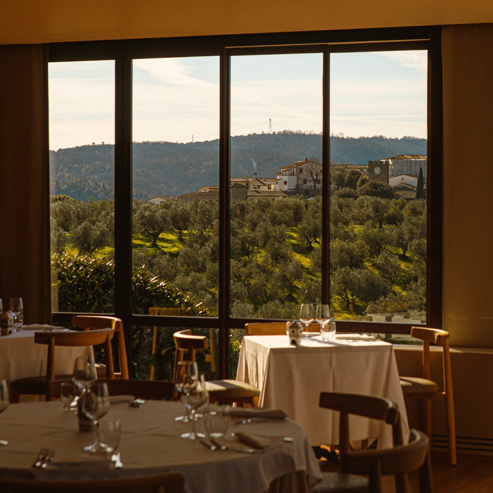 Interior view of a dining space with tables overlooking a window out onto the hills.