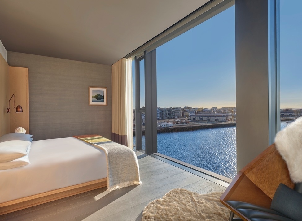Modern bedroom at The Reykjavik Edition with a large window showing a waterfront view of Reykjavik, Iceland.
