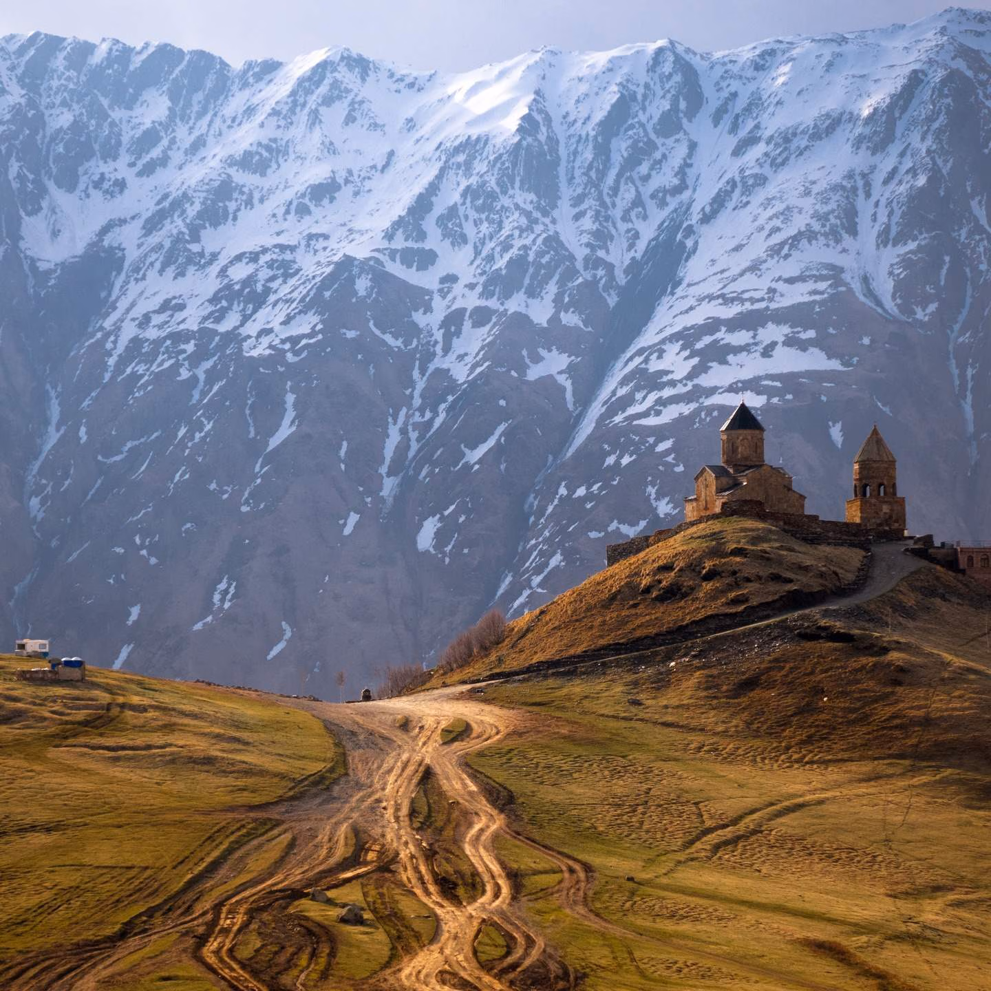 Gergeti Trinity Church on a hill in Kazbegi National Park with snowy mountains in the background, Georgia