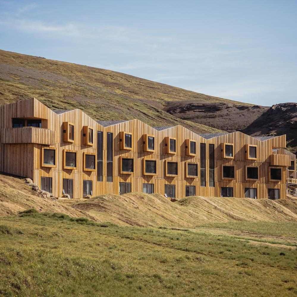 Exterior view of Highland Base lodge in Iceland in summer with green hill and blue sky