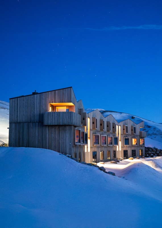 Highland Bases lodge lit up at night time with gently glowing lights reflecting on the snow