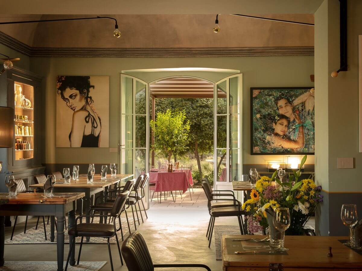 A restaurant dining room decorated with modern art, with double doors open to an outdoor terrace