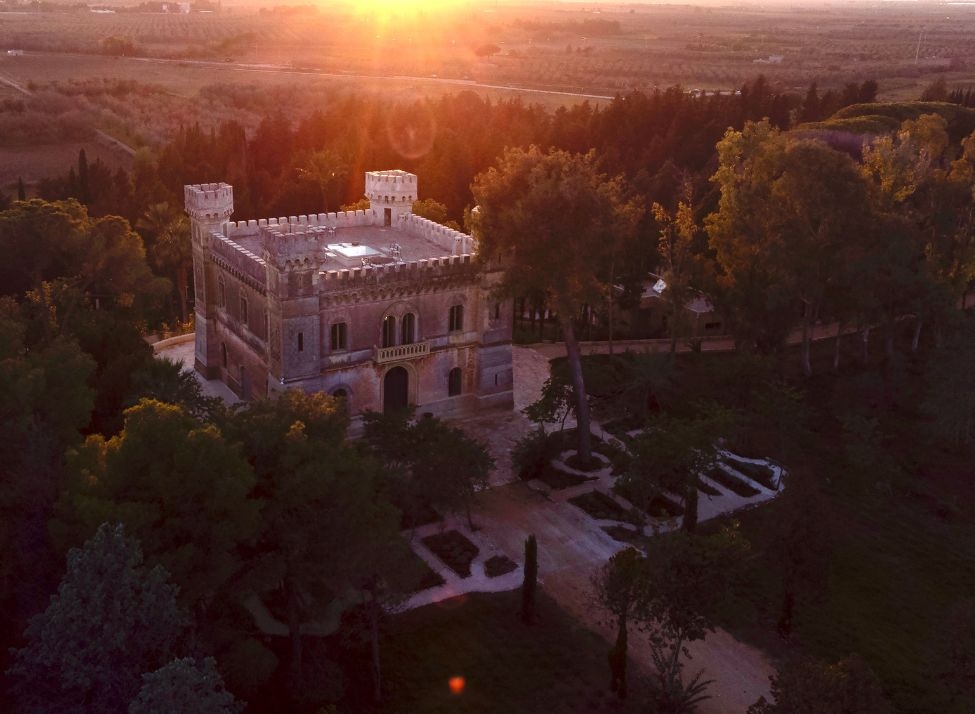 A wide view of Castle Elvira at sunset, seen from above and surrounded by gardens and trees