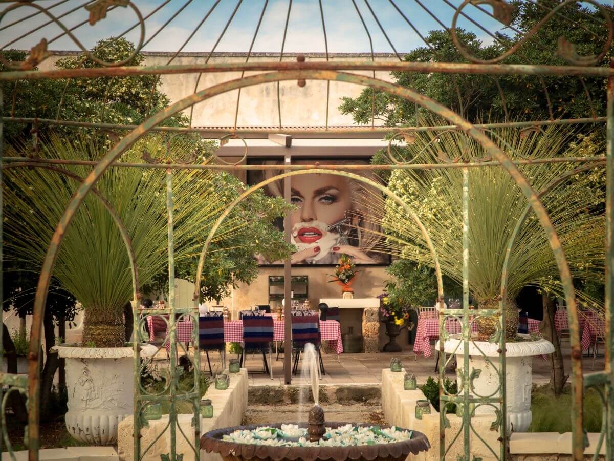 An outdoor restaurant terrace with a fountain, plants and modern art