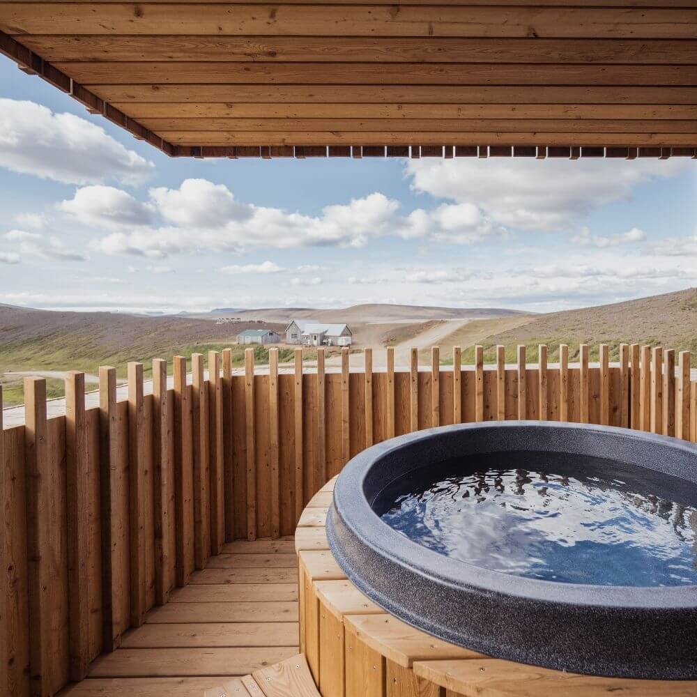 A wooden balcony with a bathtub overlooking the mountains