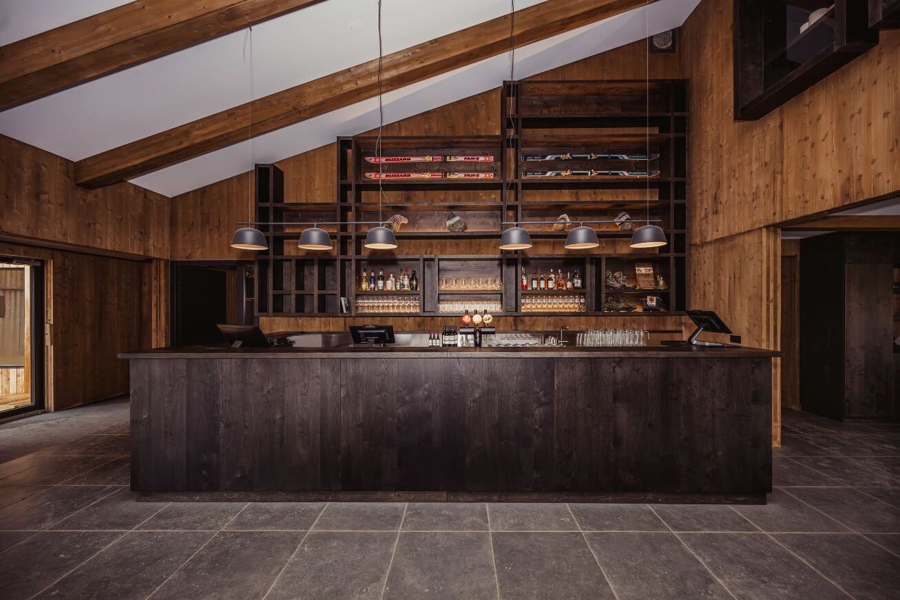 A hotel bar made of dark wood under a slanted ceiling
