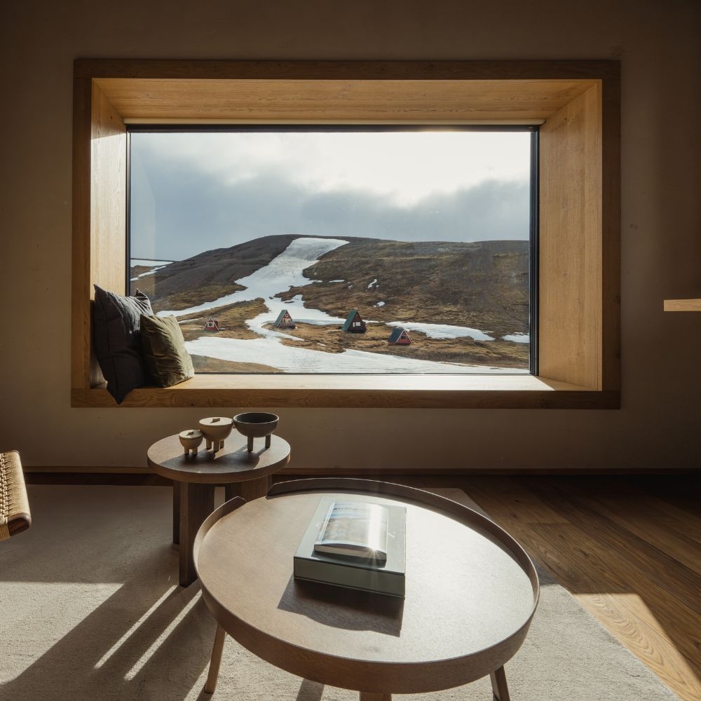 A sitting area with a large picture window overlooking a snowy mountain.