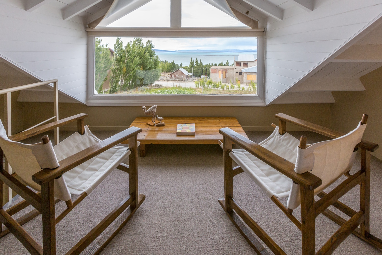 Two linen rocking chairs facing a large picture window overlooking the lake.