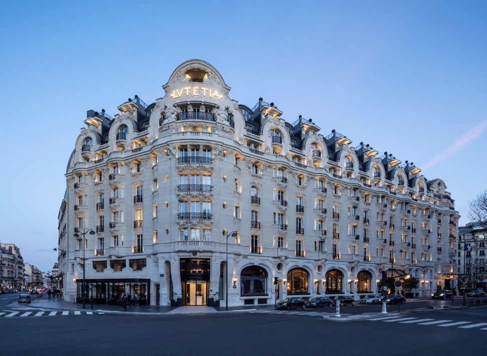 An exterior wide view of the Mandarin Oriental Lutetia hotel illuminated at dusk