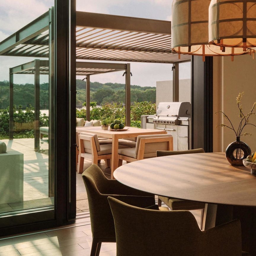 A photo of the dining table in a villa at Rosewood Miyakojima, with the patio and BBQ area behind it.