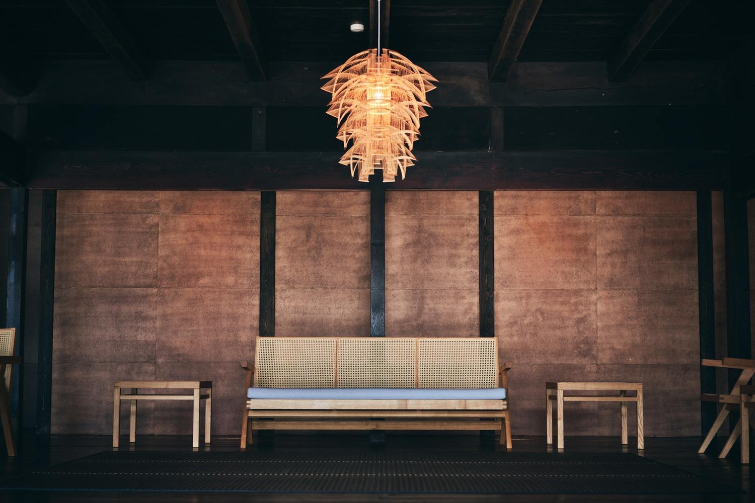 The lobby of the Zenagi hotel, with a sofa and wooden tables beneath a bamboo chandelier