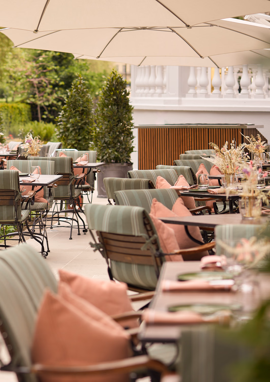 An outdoor patio seating area with tables and chairs with green and pink cushions.