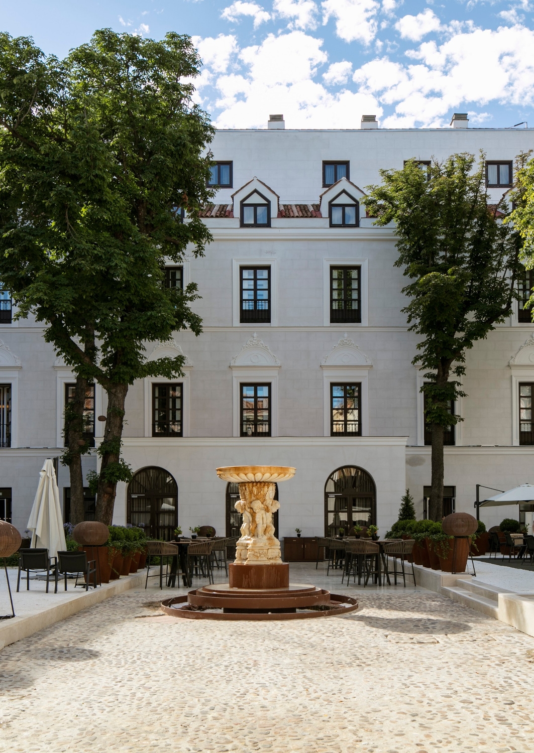 Exterior of a grand entryway to a white historic building with two trees.