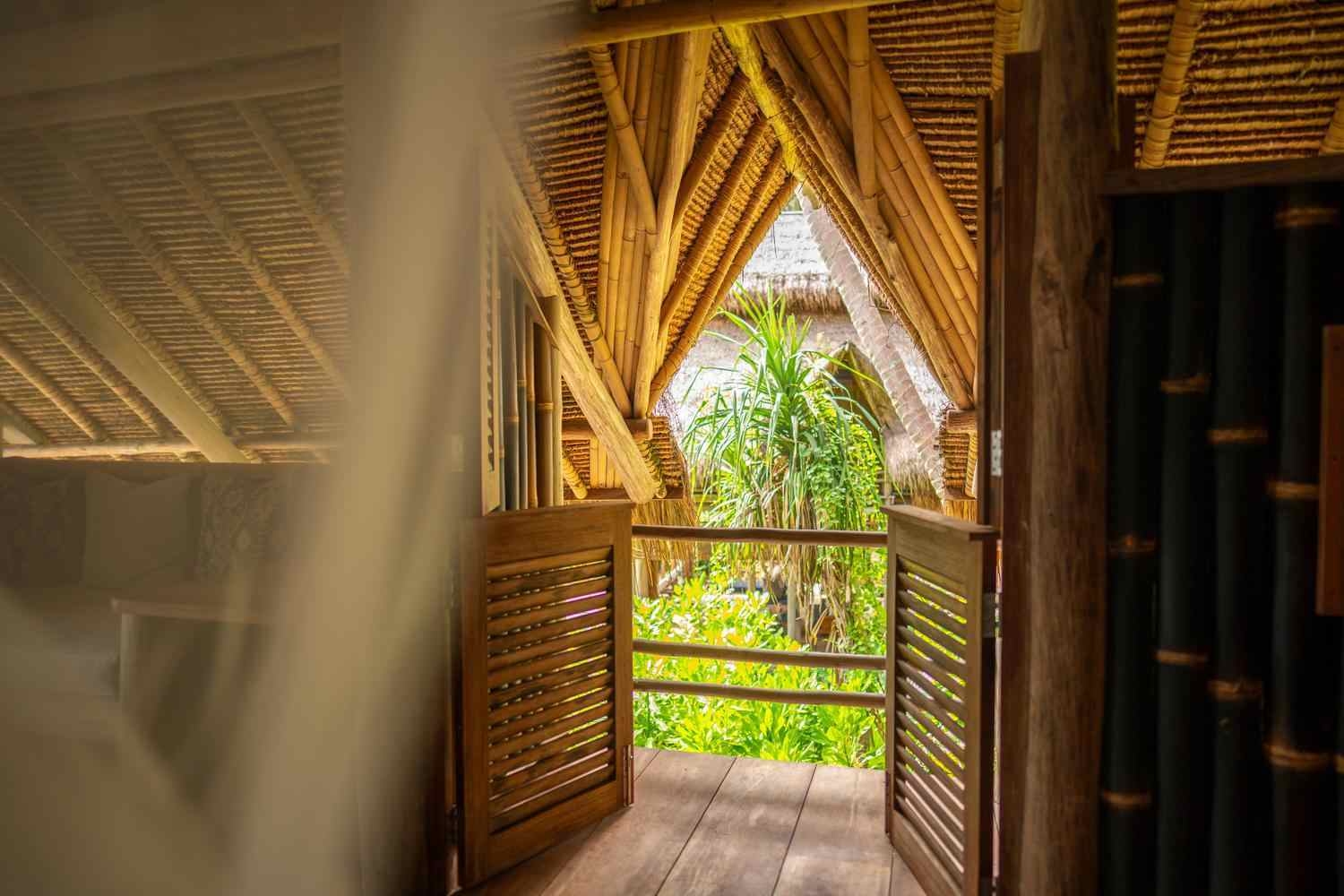 A soft focus shot of a wooden villa structure from the inside looking out, with trees visible from the balcony.