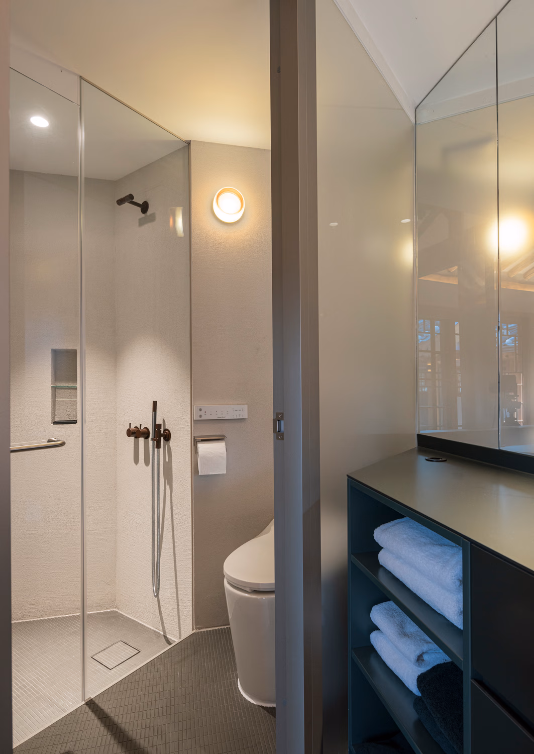 Interior of a bathroom in a traditional Korean hanok house hotel with a big mirror, corner shower and toilet.