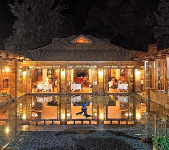 View of the dining room of Arusha Coffee Lodge from across the fountain at night, Arusha Tanzania