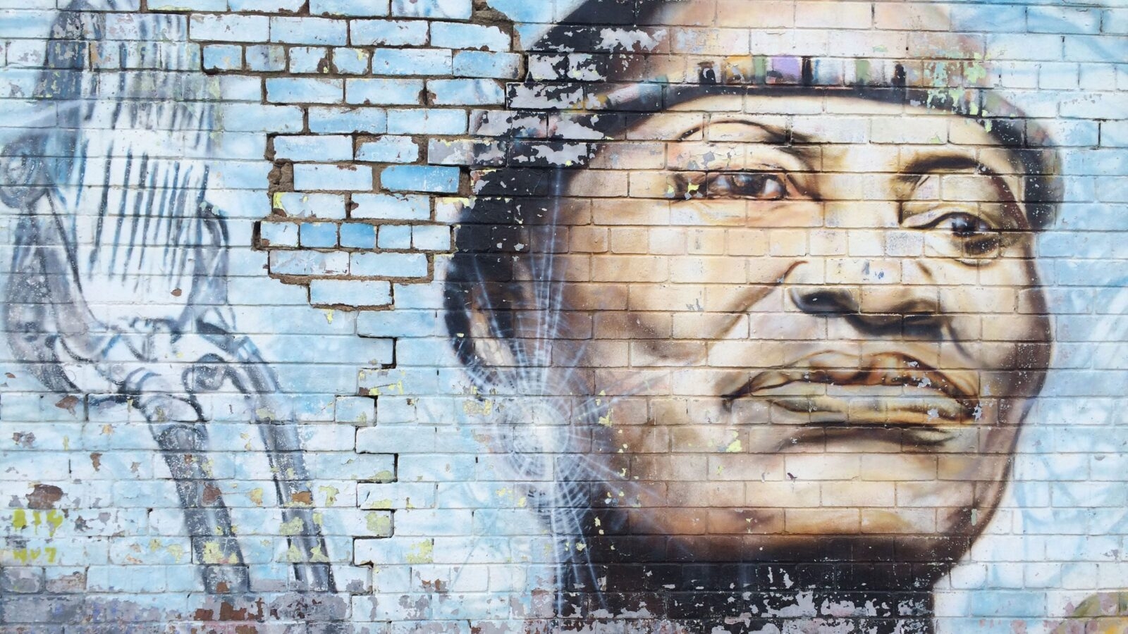 Colorful mural of a person's face painted on a weathered brick wall during luxury Johannesburg trips.