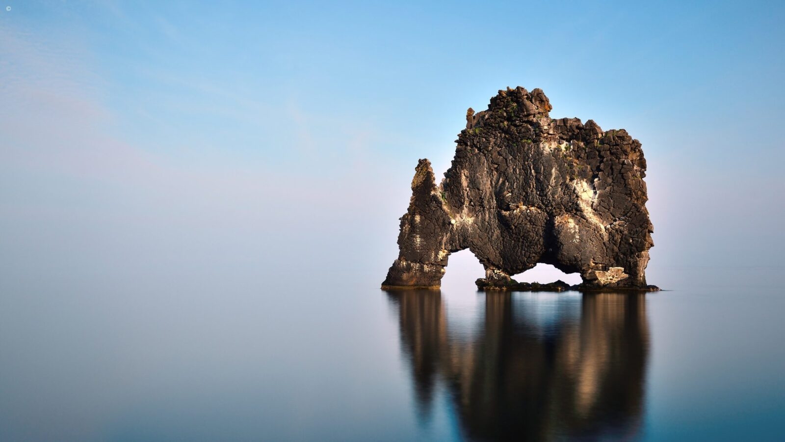 Hvítserkur rock formation rising from the glassy water in northern Iceland