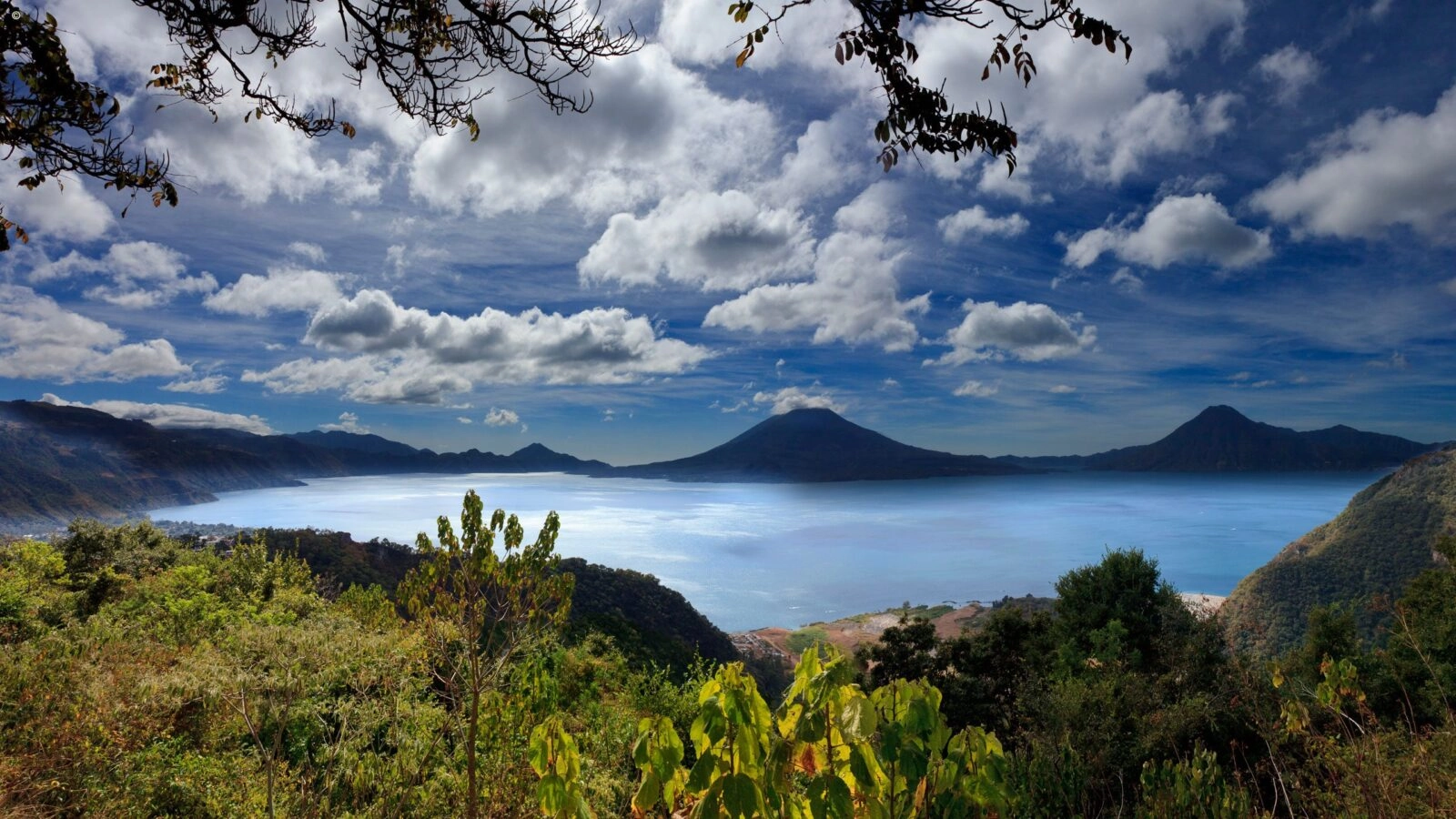 Panoramic view of Lake Atitlan in Guatemala, surrounded by mountain peaks on a sunny day