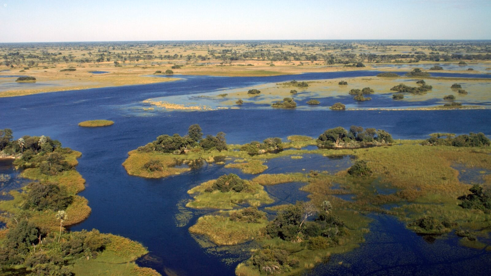 Aerial view of blue waterways and green islands on luxury Okavango Delta safaris.