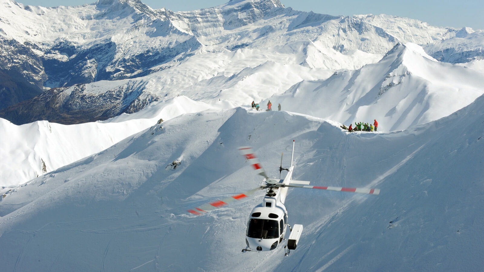 A helicopter flying over thick snowy mountains