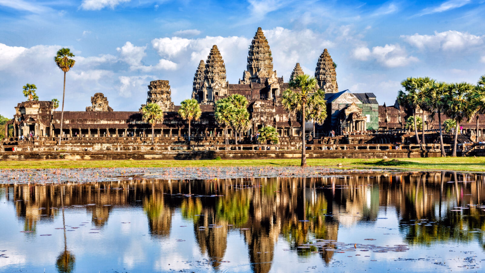 The majestic spires of Angkor Wat reflect perfectly in the still water of the surrounding lily pond during Asia honeymoons.