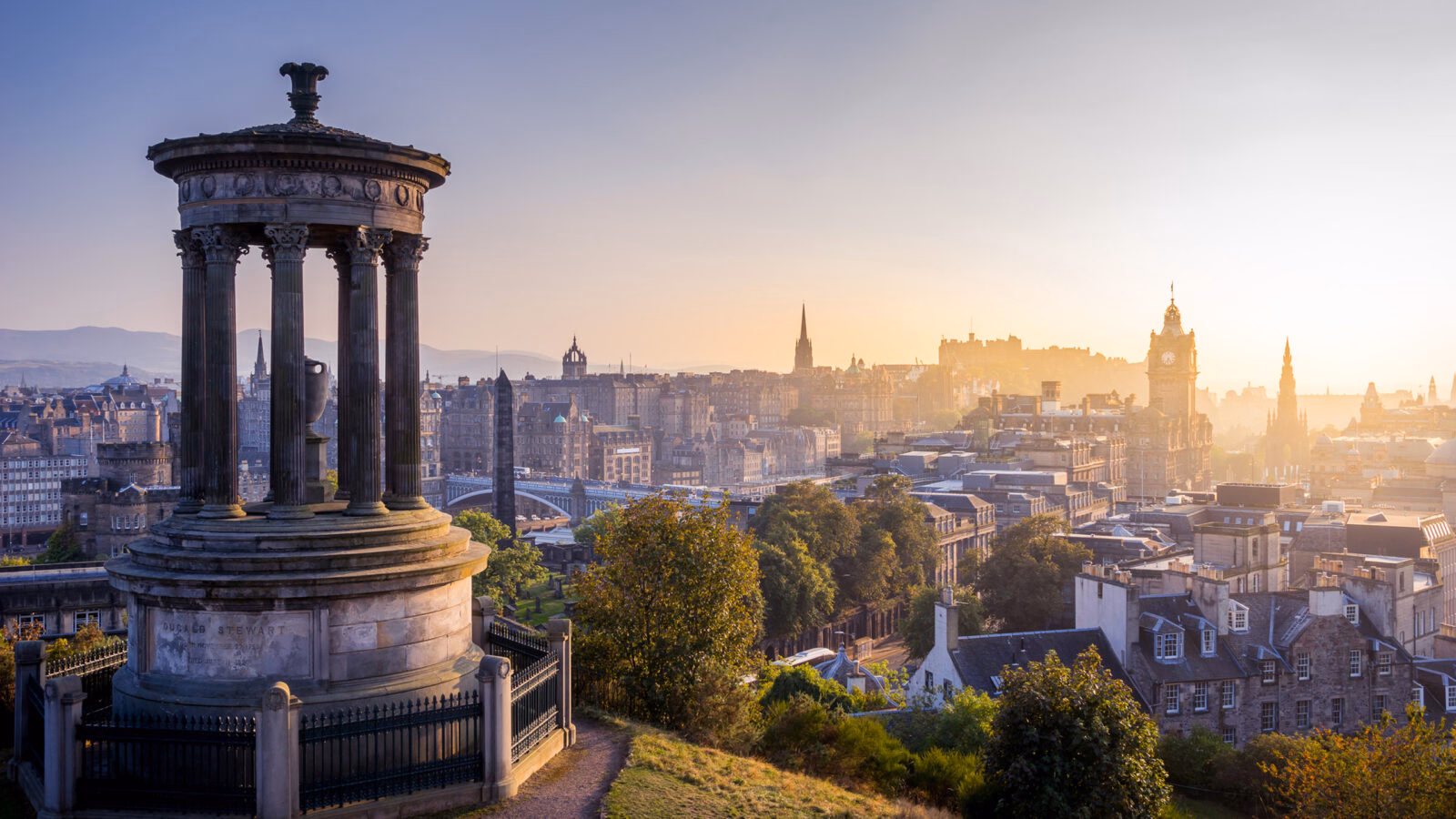 The Dugald Stewart Monument on Calton Hill overlooking the Edinburgh city skyline.