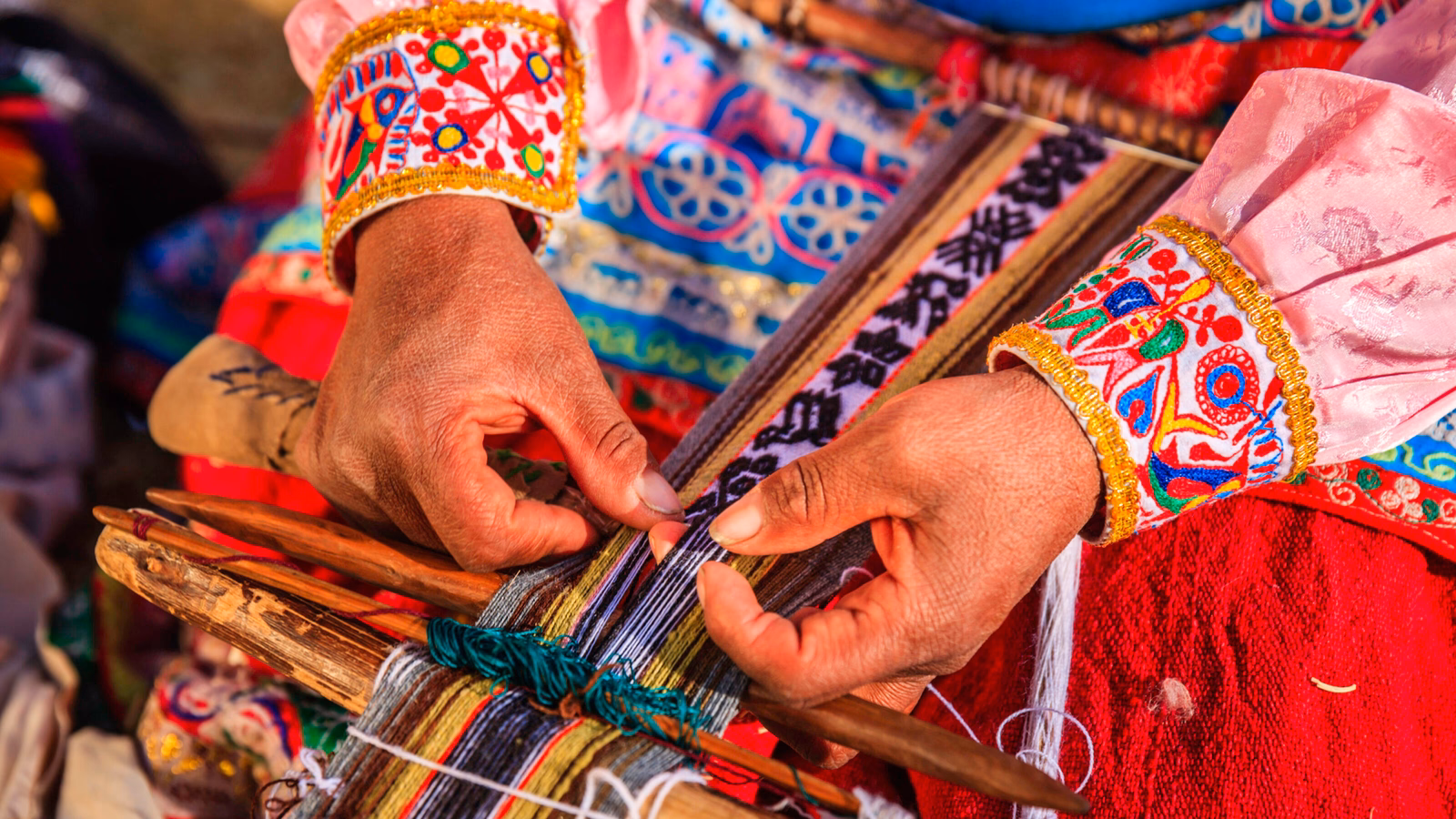 A woman's hand weaving traditional, colourful wool fabric in Peru