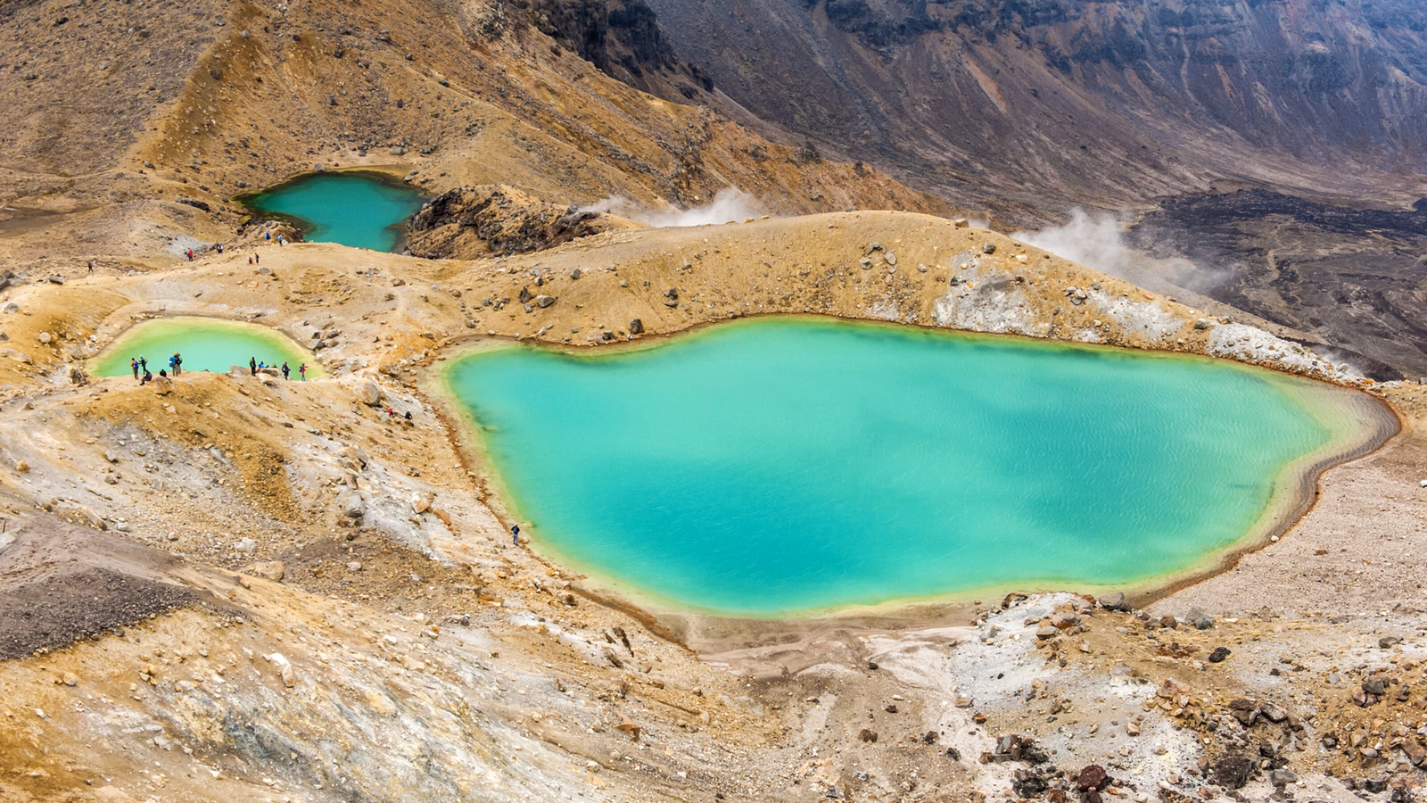 Three vibrant turquoise volcanic lakes surrounded by rocky, barren terrain.