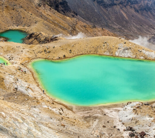 Three vibrant turquoise volcanic lakes surrounded by rocky, barren terrain.