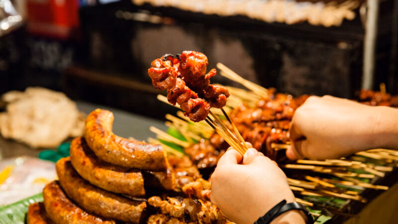 CHIANG MAI, THAILAND: Man buys skewered grilled pork