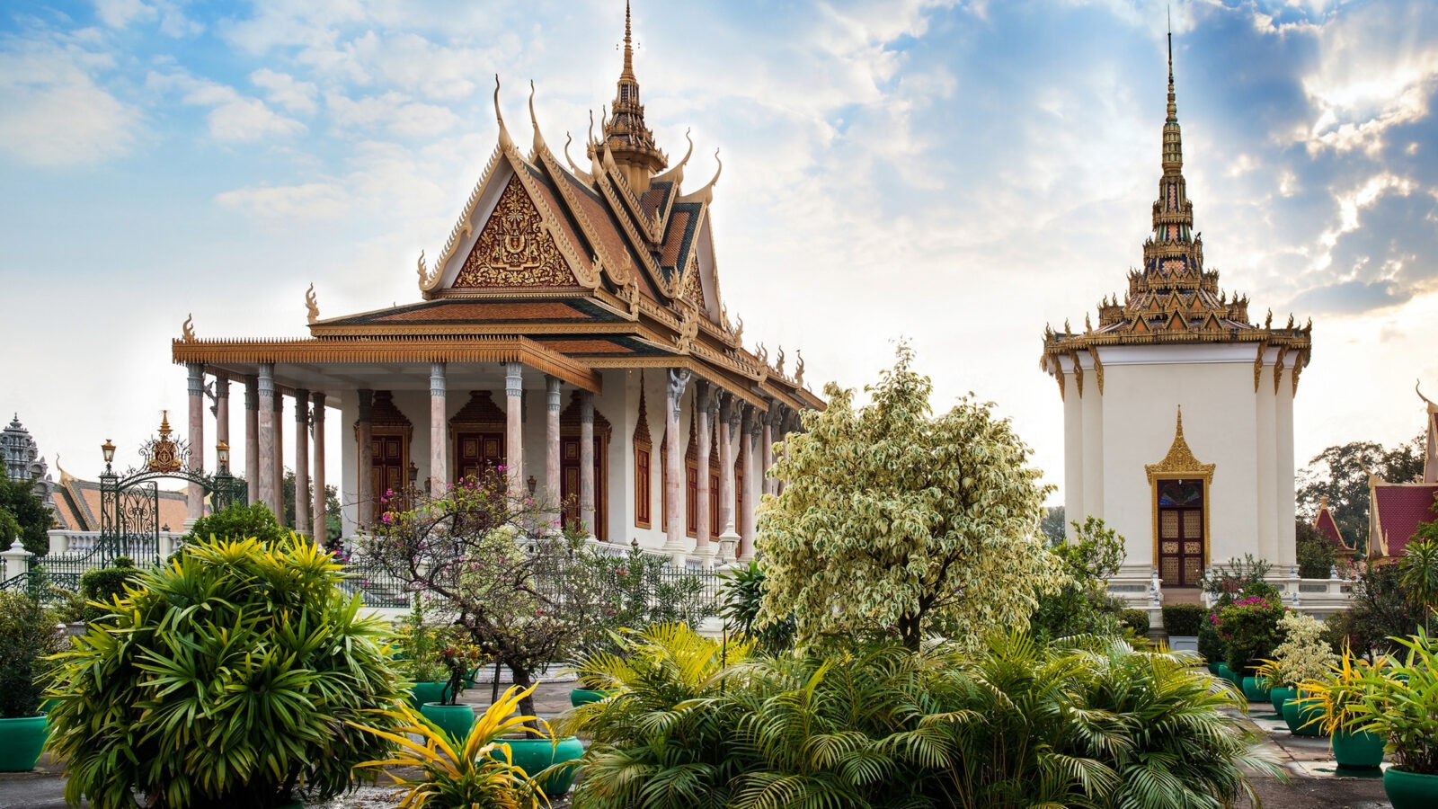 Ornate traditional Cambodian temple buildings with gold spires and manicured gardens at the Royal Palace.
