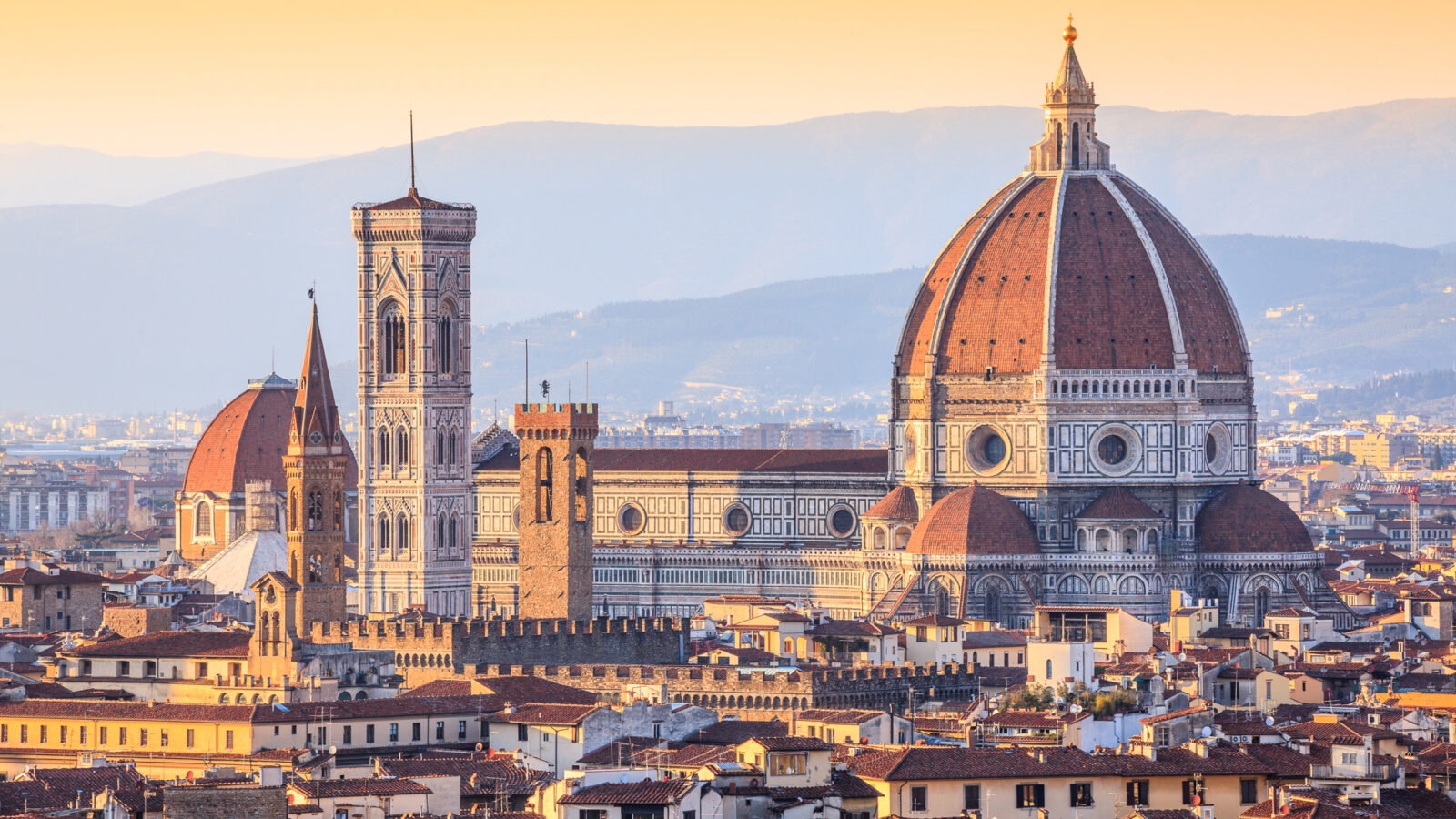 High angle view of Florence, Italy, featuring the Duomo and bell tower during a golden sunset.