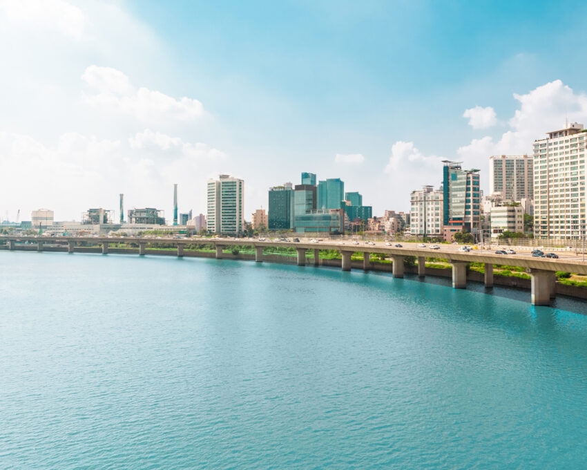 Different cars passing highway road along Han river with business and residential area near it - Seoul, South Korea