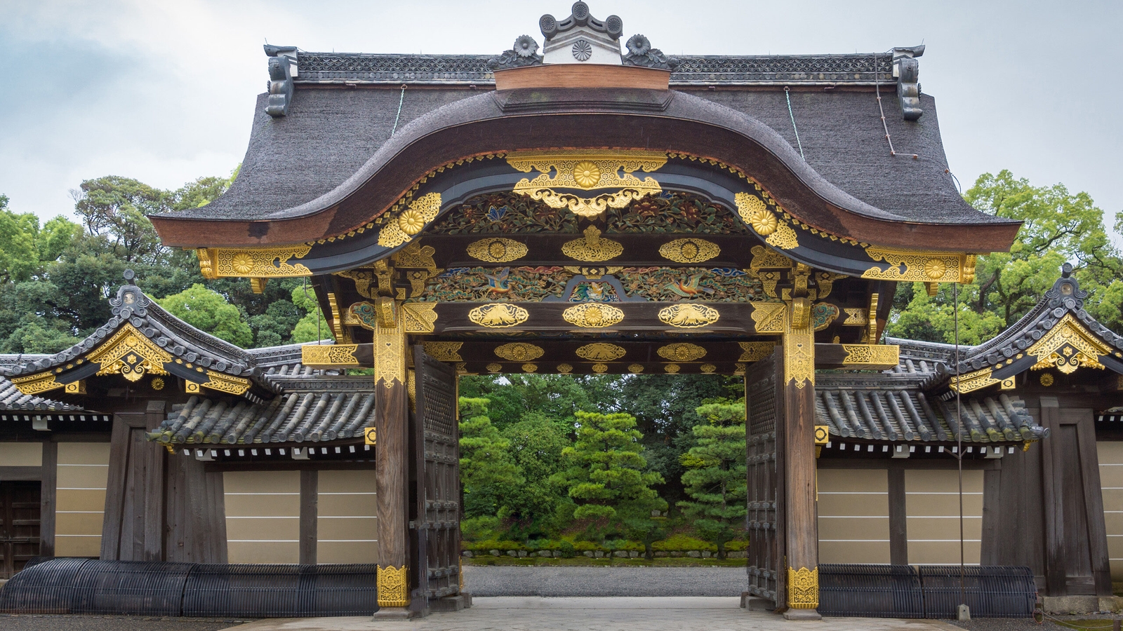 The highly decorated Karamon Gate of Nijo Castle featuring golden details, dark wood carvings, and a curved roof line.