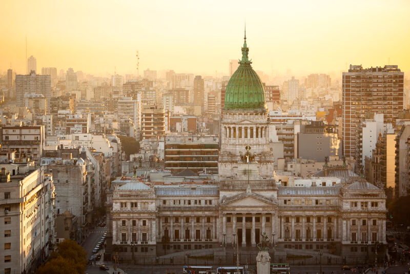 The large, domed National Congress building in Buenos Aires, surrounded by city buildings at sunset. Luxury Argentina vacations.