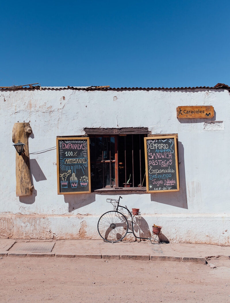 A white building with chalkboard menus and a decorative bicycle, ideal for luxury Chile tours.
