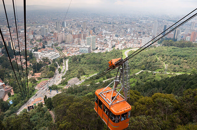 n orange cable car descends towards the large, sprawling cityscape of Bogotá below, offering scenic views as part of Luxury Colombia Holidays.