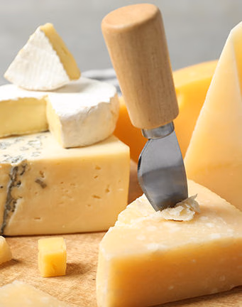 A variety of artisanal cheeses on a wooden board for luxury France vacations.