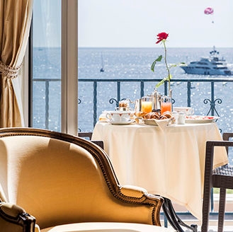 A balcony breakfast table overlooking the sea and a yacht during luxury France holidays.