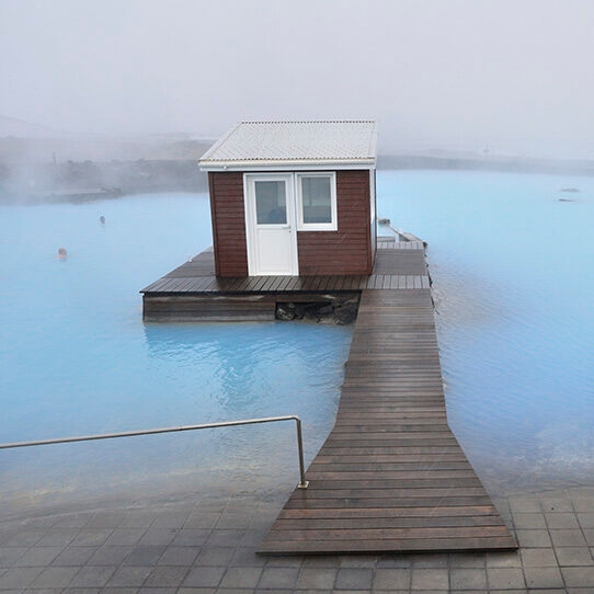 Jacada Iceland - a steaming blue thermal pool with a wooden jetty and small hut