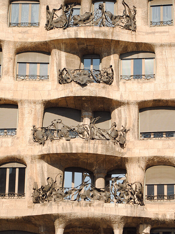 Close-up of four levels of the wavy stone facade and organic wrought-iron balconies of Casa Batlló, for luxury Spain holidays.