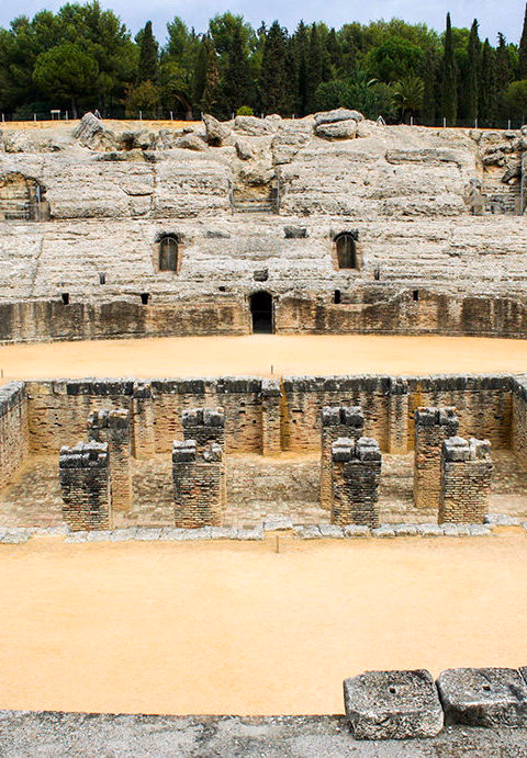 Preserved ruins of a Roman amphitheater with lower-level brick structures and stone seating, ideal for luxury Spain vacations.