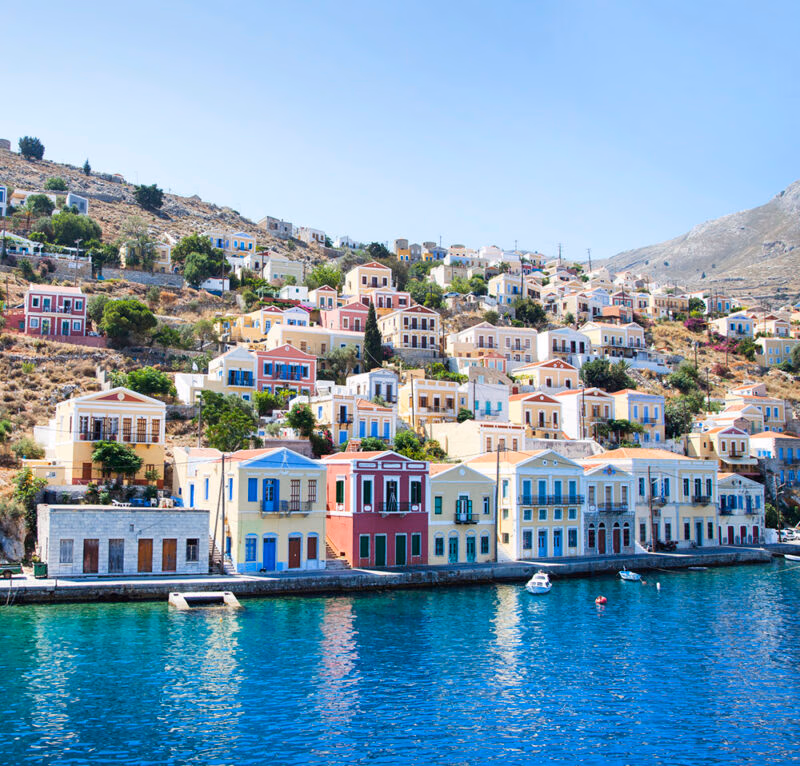 Luxury Greece Tours - Beautiful city of Symi, Greece, with colourful cube-shaped buildings lining the waterfront