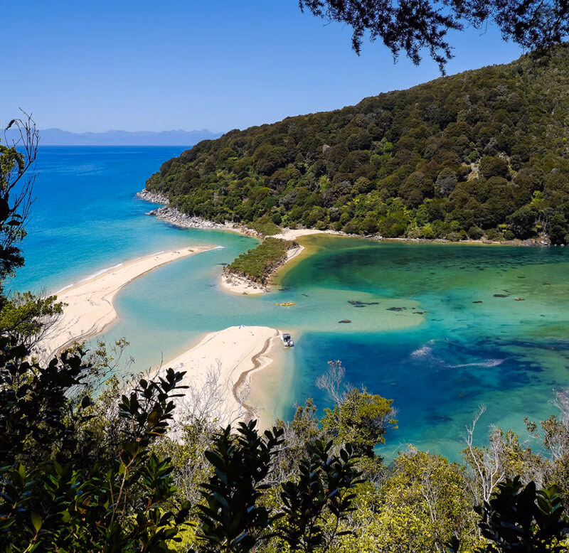 Aerial view of a turquoise lagoon and golden sand beaches during luxury New Zealand tours.