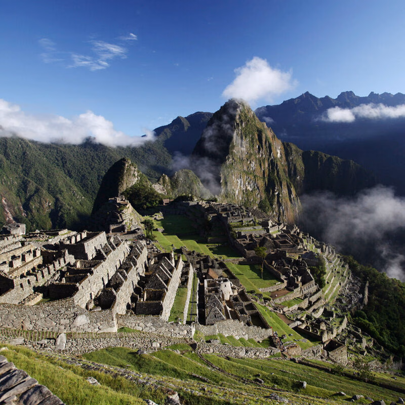 An aerial view of Machu Picchu's extensive stone ruins and terraces, with the peak of Huayna Picchu shrouded in clouds, excellent for luxury Machu Picchu tours.